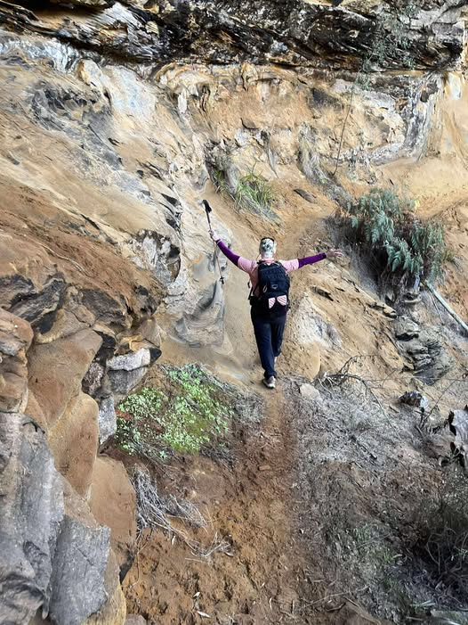 one hiker with arms stretched to the heavens show us the majestic height of the the sandstone cliff face